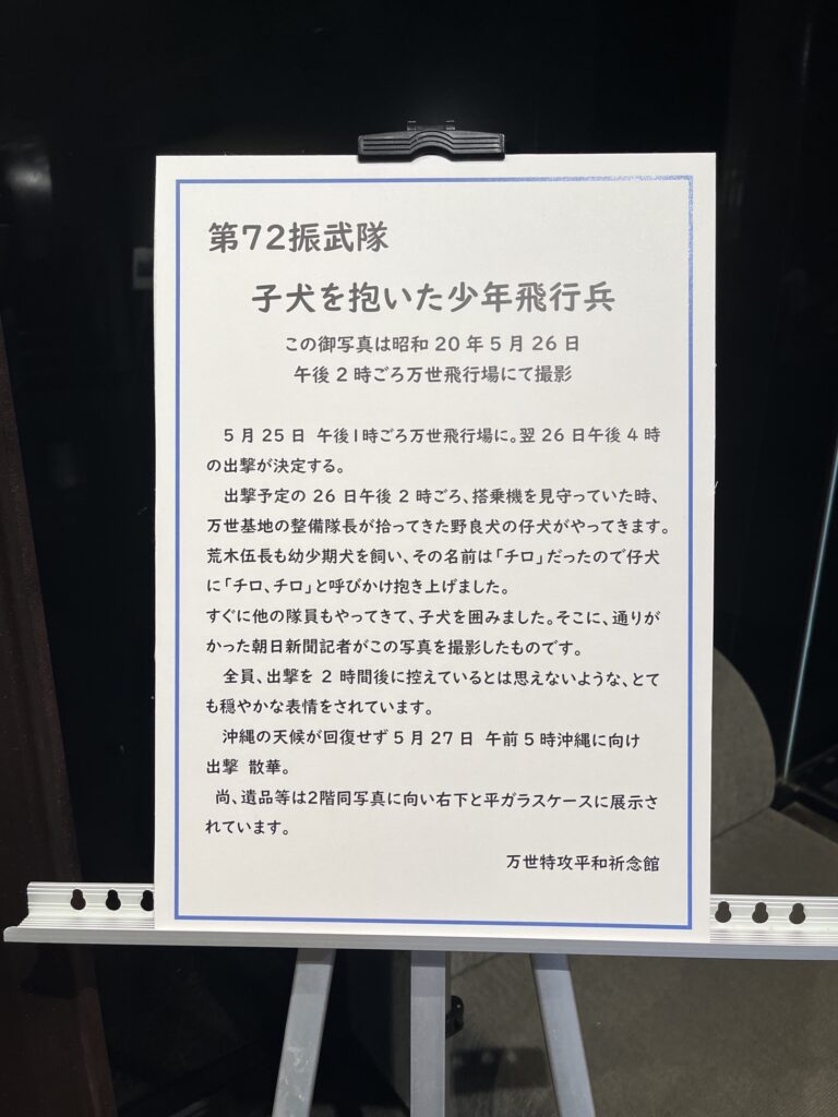 子犬を抱いた少年飛行兵の画像の説明文が書いてあるパネル